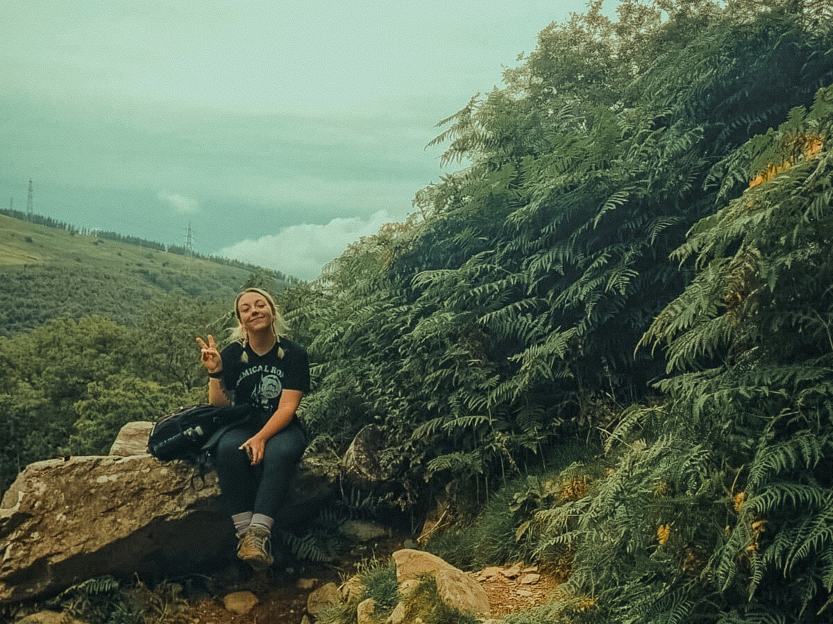 a woman sat on a rock during a climb up a mountain